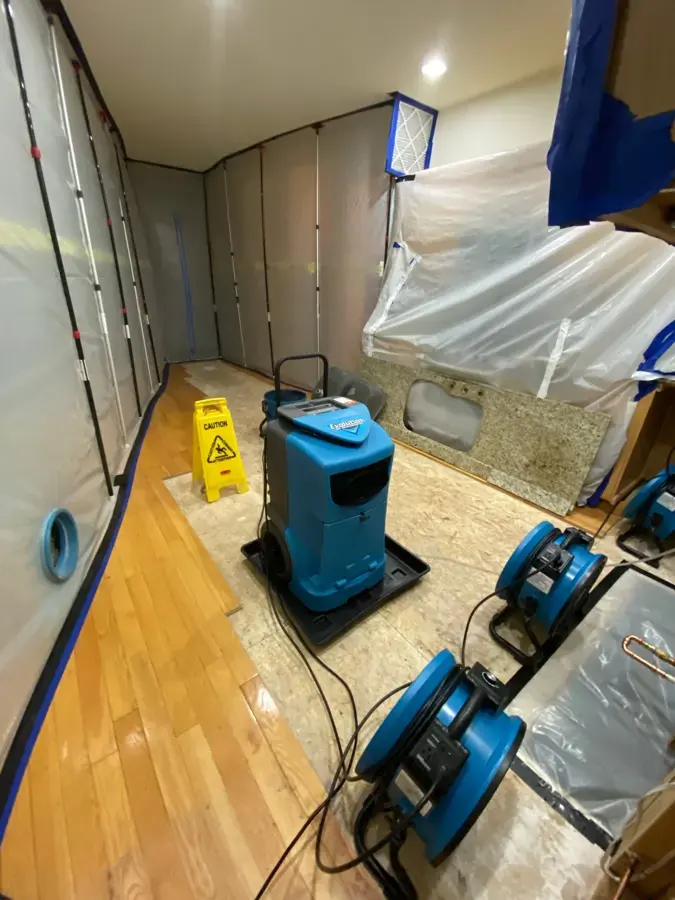 Air movers and a dehumidifier drying a hardwood floor behind plastic containment in a Duvall, WA home