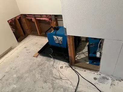 Dehumidifier drying an opened wall and subfloor after a leak