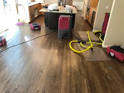 Dehumidifier and drying hoses running across a hardwood kitchen floor