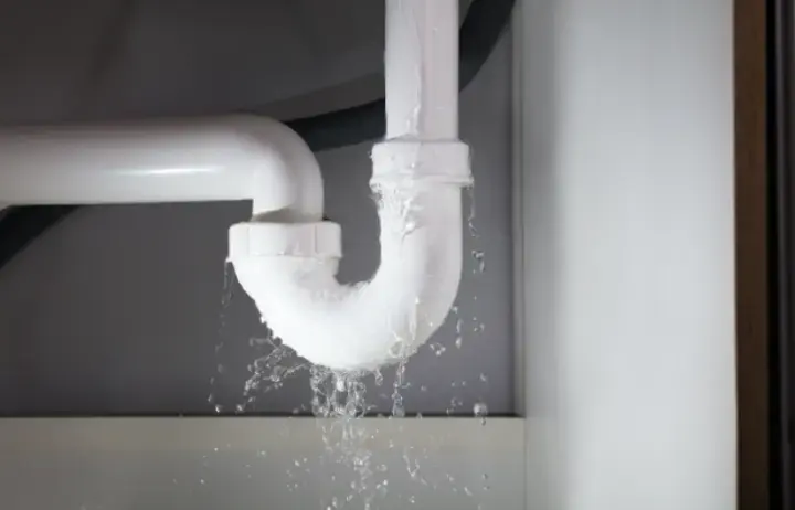 Burst drain pipe spraying water under a sink in Sammamish, WA