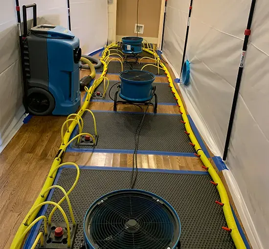 Hardwood drying mats with yellow hoses and a dehumidifier inside plastic containment in Sammamish, WA